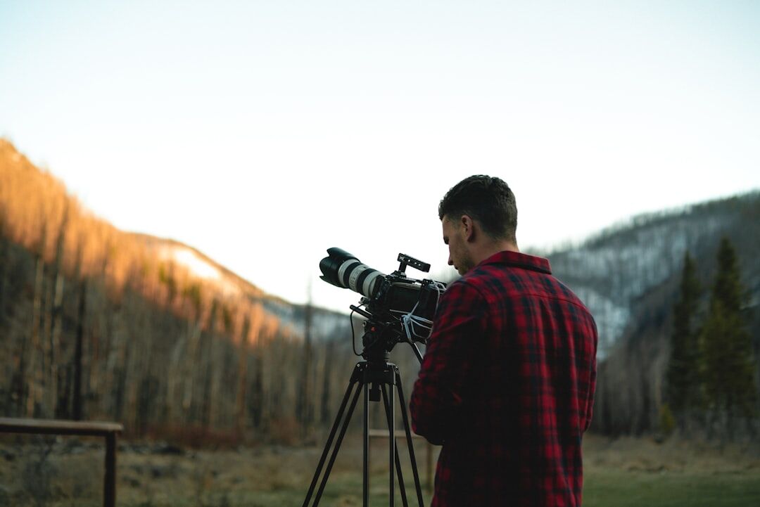 Videographer filming a documentary scene with a camera on a tripod outdoors