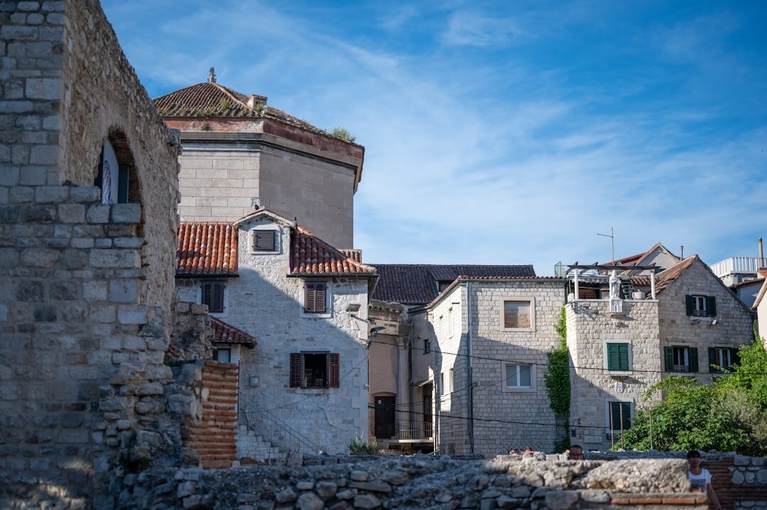 Elderly woman sitting in front of a stone house in rural Croatia
