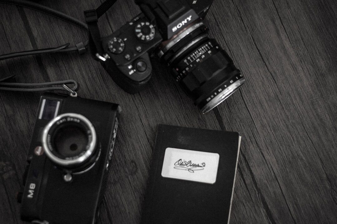 Photographer editing black and white photographs on a laptop with a camera and prints on the desk